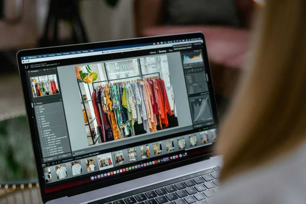 Close-up of a laptop displaying photo editing software with clothes rack in view.